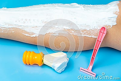 Procedure for preparing legs for hair removal with a pink disposable razor on a blue background, next to it is an orange shaving Stock Photo