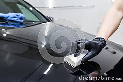 The process of applying a nano-ceramic coating on the car`s hood by a male worker with a sponge and special chemical composition Stock Photo