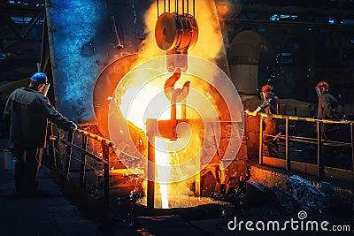Process of casting in foundry, liquid molten metal pouring in ladle. Heavy metallurgy industry Editorial Stock Photo