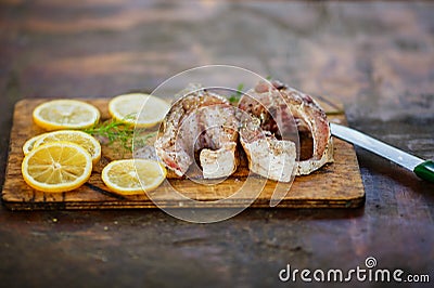 The process of cooking fish, two fresh raw tasty pieces of fish with lemon slices and parsley on wooden Board Stock Photo