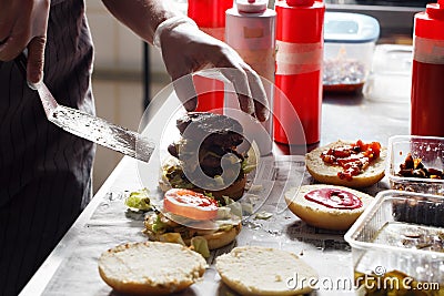 Process of cooking hamburger. chef on the kitchen table making out the ingredients of the Burger. Beef Patty cooked on Stock Photo