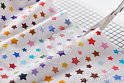 Process cutting fabric with a pattern of colorful stars by scissors on craft mat Stock Photo