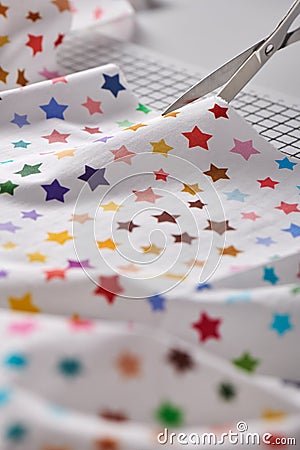Process cutting fabric with a pattern of colorful stars by scissors on craft mat Stock Photo