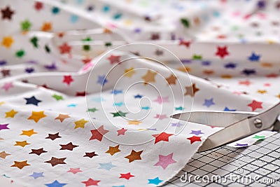 Process cutting fabric with a pattern of colorful stars by scissors on craft mat Stock Photo