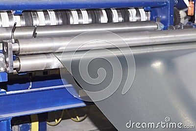 Process of cutting a wide sheet of metal into narrow strips on a machine Stock Photo