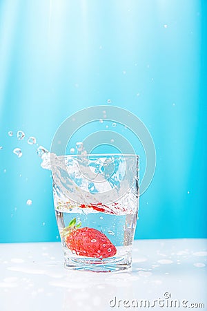 Process of Falling of Ripe Juicy Floating Strawberry into Glass of Fresh Clear Water. Beautiful High Splashes Drops Stock Photo