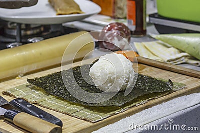 The process of making sushi and rolls with cucumber. Rice on nori sheet Stock Photo