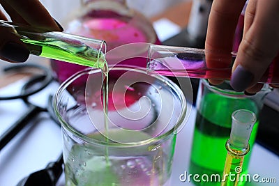 The process of mixing two reagents, purple and green, in a beaker. Stock Photo