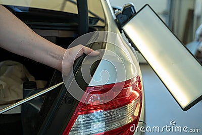 Process Of Paintless Dent Repair On Car Body. Technician s Hands With Puller Fixing Dent On Rear Car Fender. PDR Removal Stock Photo
