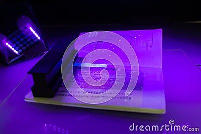 Process of the passport visa checking, close-up. The study of protective elements of the document in ultraviolet light. High Stock Photo