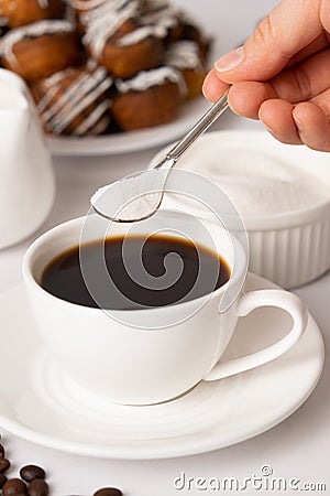 The process of pouring white sugar from a spoon into a white cup of coffee. Sugar addict, diabetes. Stock Photo