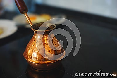 Process of preparing a classic breakfast: fried eggs in a frying pan, a classic Turkish Turk for cooking coffee on a glass hob. Stock Photo