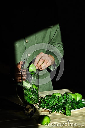 Process of preparing green detox smoothie with blender, young man cut apples Stock Photo