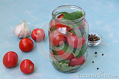 The process of preparing pickled tomatoes with grape leaves and garlic. Location on a light blue background Stock Photo