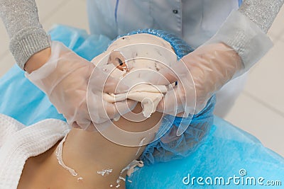 The process of removing the alginate mask by a cosmetologist in a beauty salon. Cleansing and moisturizing the skin Stock Photo