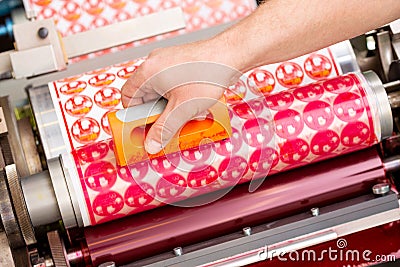 Process of removing possible dust debris on polymer plate in magenta print tower station with sticky roll on flexographic press. Stock Photo