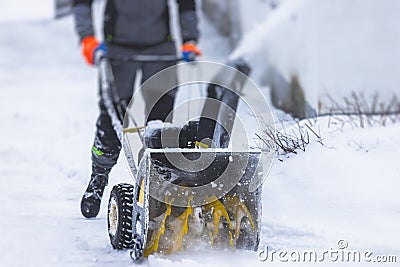Process of removing snow with portable blower machine, worker dressed in overall workwear with gas snow blower removal on the Stock Photo