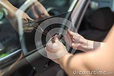 Close up of worker pulling off sun protection tinted foil from side car window Stock Photo