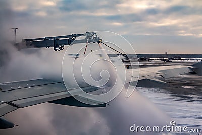A process of spraying anti-icing white fluid the rear part of the wing of a plane at the airport in winter Stock Photo
