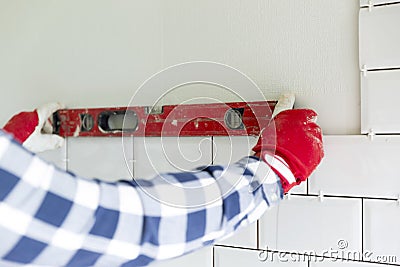 Process of tiling the tiles in the kitchen. Contractor measuring Stock Photo