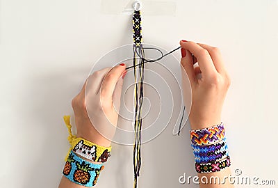 Process of weaving knot for DIY friendship bracelet. Female hands with many handmade bracelets on wrists. step by step. Stock Photo