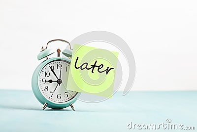 Procrastination, delay concept. Bad time management. Word later sticked to alarm clock Stock Photo