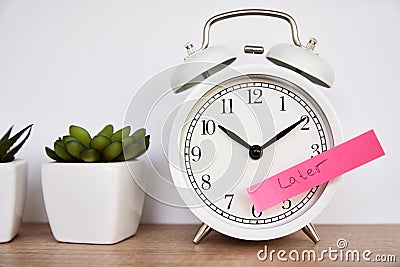 Procrastination and delay concept. Sticky note with word later on white alarm clock. Urgency time Stock Photo