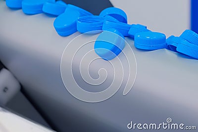 Production line - many blue plastic bottle caps falling from conveyor belt Stock Photo