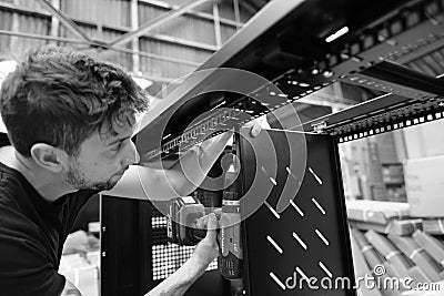 Production line worker seen assembling data cabinets at a factory. Editorial Stock Photo