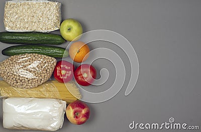 Products for delivery - cereals, peas, sugar, pasta, cucumbers, tomatoes, apples, orange on a gray background. Place for text Stock Photo