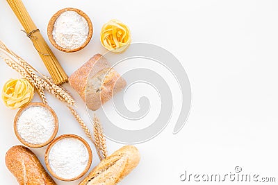 Products made of wheat flour. White flour in bowl, wheat ears, fresh bread and raw pasta on white background top view Stock Photo