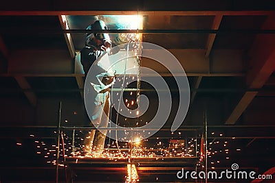 Profesional welder in protective uniform and mask welding metal construction in the industrial object Stock Photo