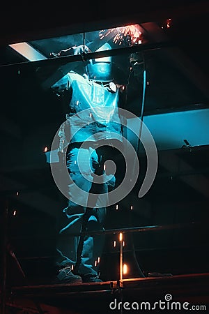 Profesional welder in protective uniform and mask welding metal construction in the industrial object Stock Photo