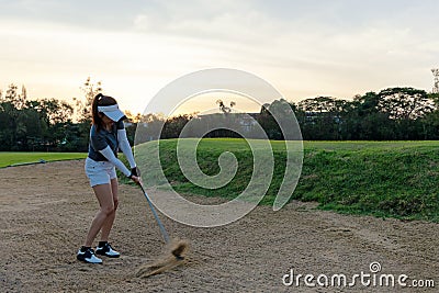 Profession asian Golfer woman hitting out of a sand trap. People with the golf course is on the sand. Hobby in holiday and vacati Stock Photo