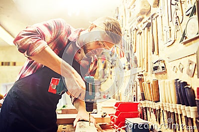 Carpenter with drill drilling plank at workshop Stock Photo