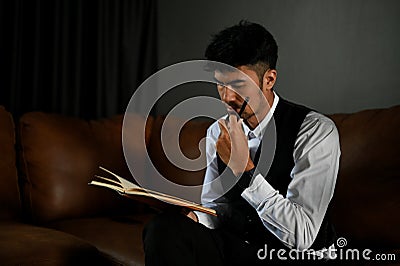 Professional adult Asian businessman focused reading something on a book Stock Photo