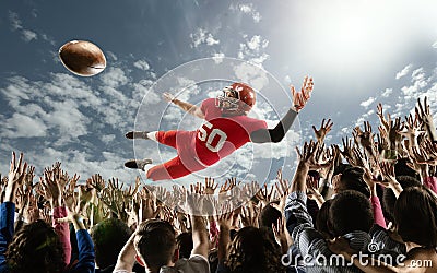 Professional american football player flies over hands of fans and catching a touchdown pass. Stock Photo