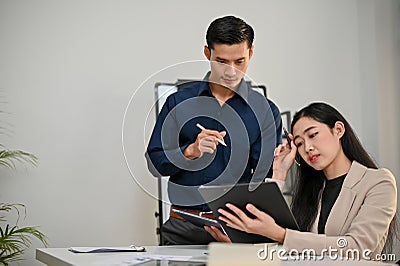 Professional Asian businessman concentrated on working with his female coworker in the office Stock Photo