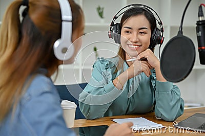 Professional Asian female podcaster enjoys interviewing her special guest in the studio Stock Photo