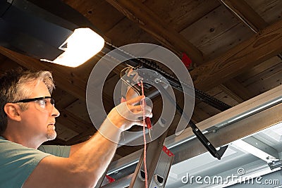 Professional automatic garage door opener repair service technician working closeup Stock Photo