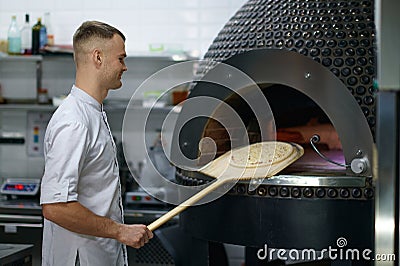 Professional baker chef making traditional italian pizza in oven Stock Photo