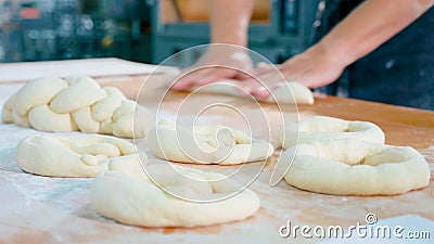 Professional baker is forming pieces of dough in bakery commercial kitchen. Stock Photo