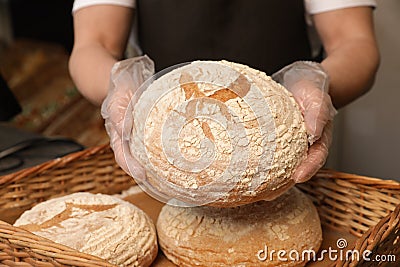 Professional baker holding loaf of bread over tray in store Stock Photo