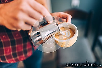 Professional Barista pouring hot milk foam and creating coffee latte art Stock Photo