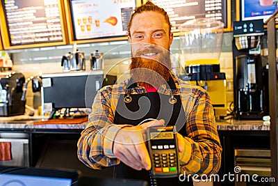 Professional barista young redhaired ginger bearded man in black apron working in coffee shop Stock Photo