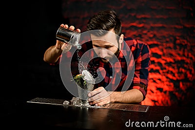 Professional bartender adding sugar powder to steel glass. Stock Photo