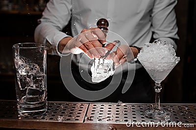 Professional bartender breaking an ice to prepare a delicious cocktail Stock Photo