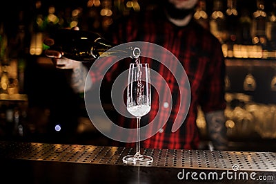 Professional bartender pourring a champagne from a bottle to a g Stock Photo