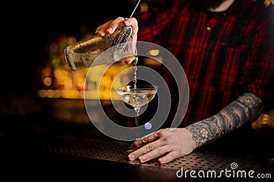 Professional bartender pourring a Twinkle achoholic cocktail drink from the measuring cup Stock Photo