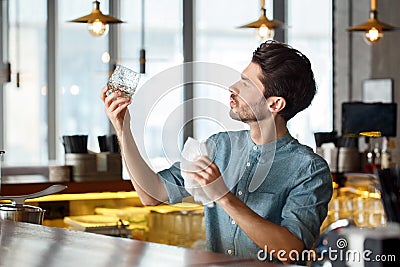 Professional Occupation. Bartender standing at counter looking at glass clarity curious Stock Photo